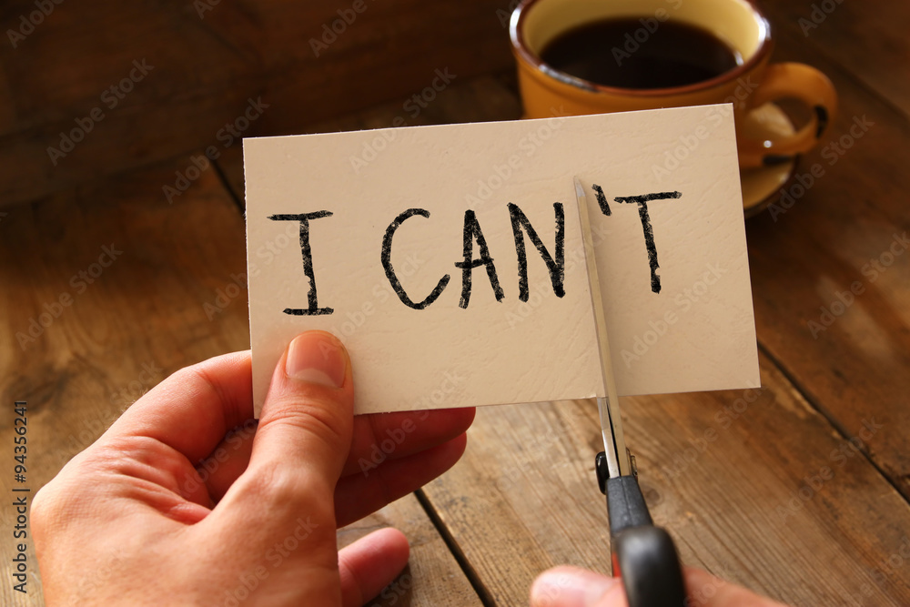 Aufkleber man hand holding card with the text i can't, cutting the word t so it written i can. success and cha