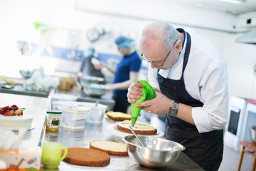 Baker prepares a cake and eclairs