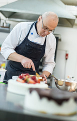 Baker prepares a cake and eclairs