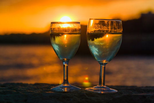 Two wine glasses on the background of sunset seascape