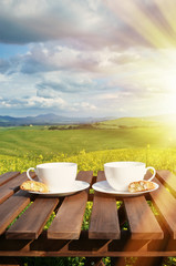 Two coffee cups and cantuccini on the wooden table against Tusca