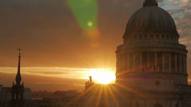 A cinematic, telephoto sunset view by St Paul's Cathedral in the City of London, England, UK. A small lens aperture was used, creating a star burst effect
