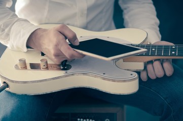 Man using mobile device and guitar