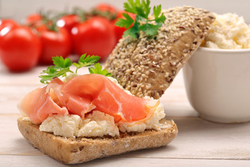 Sandwich with white cottage cheese and ham on white wooden backg