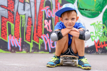 Attractive young boy sitting on his skateboard