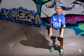 Handsome little boy holding his skateboard