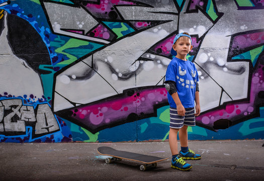Little boy standing in front of vibrant graffiti