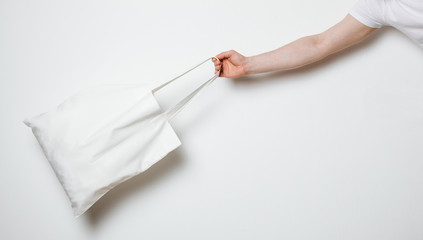 Male hand holding white textile bag