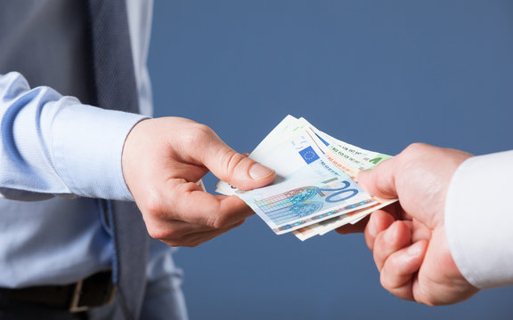 Businessman's  hands exchanging euro on blue background
