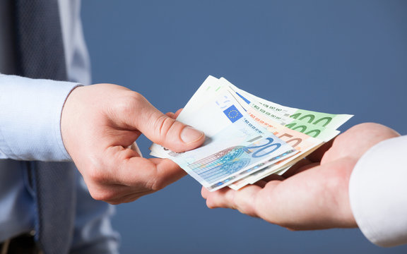Businessman's  hands exchanging euro on blue background