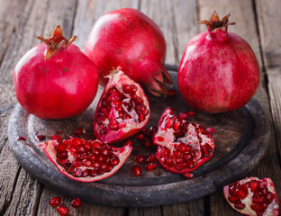 Juicy pomegranates,whole and broken on wooden background.selective focus.