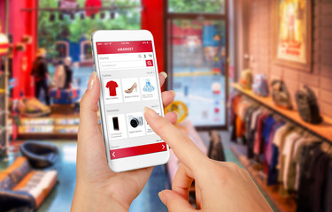 Smart phone online shopping in woman hand. Shopping center in background. Buy clothes shoes...