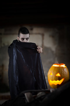 Vampire Hiding Behind His Cape While Standing Next To Jack O' Lantern