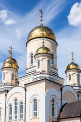 Fototapeta na wymiar Golden domes of Russian orthodox church with cross against blue