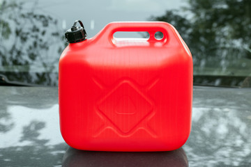 New red plastic jerrycan stands on car hood