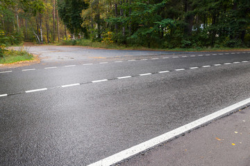 Wet rural asphalt road with dividing line
