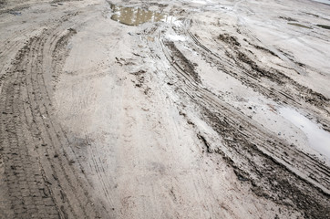 Tire tracks over mud dirty road with puddles