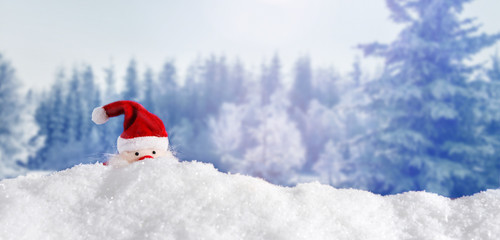 Weihnachtsmann versteckt sich hinter Schneewehe im Wald