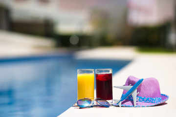 Glasses of juice, straw hat, sunglasses and airplane model on