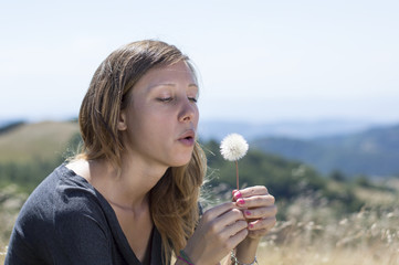 Girl blowing a dandelion in the field