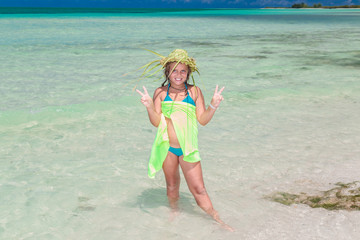 joyful happy smilinig styled little girl in swimming suit standing in the ocean at cuban Cayo Coco island