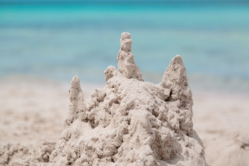 Fototapeta na wymiar An interesting nicely built sand castle using a child's fantasy on the background of turquoise tranquil inviting ocean