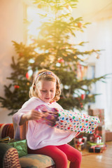 next the Christmas lighted tree, little girl opening a gift