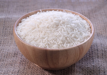 Fototapeta na wymiar Rice in a wooden bowl on sackcloth background