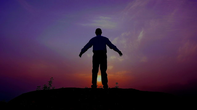 
Silhouette of meditating man (prayer) at top with  raised hands  at sunrise time. 4K 3840x2160

