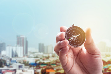 compass in hand on town of blurred blue color with lighting flar