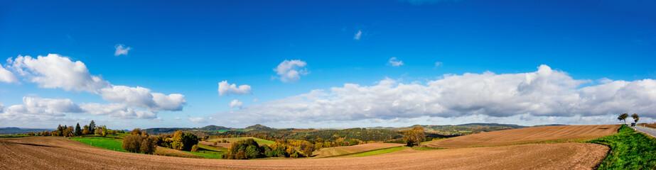 Panorama of foothill valley with plowed field in the spring