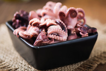 Boiled small octopus on a black plate