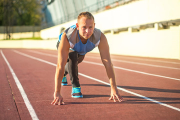 Athletic man standing in  posture ready to run on a treadmill.