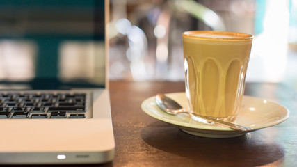 Hot art Latte Coffee in a cup and laptop on wooden table in Coff