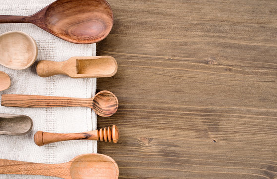Various wooden spoons at left side of wooden table background