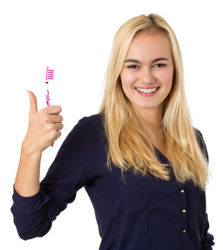 Blonde junge Frau zeigt Daumen hoch mit Zahnbürste