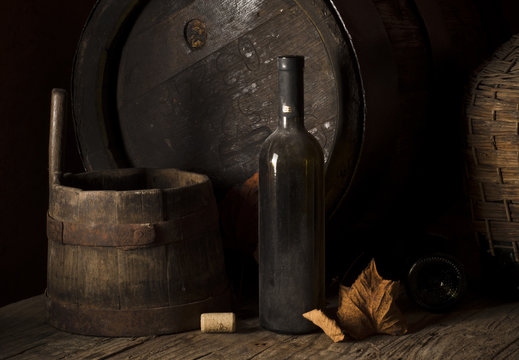 Still life with wine bottles, glasses and oak barrels.