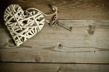 wicker heart handmade with the key lying on a wooden base . top