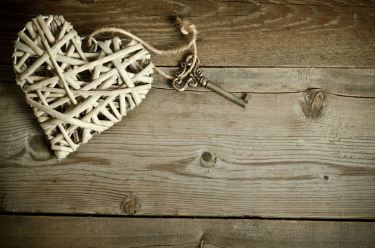 wicker heart handmade with the key lying on a wooden base . top