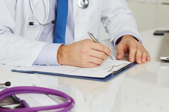 Male Medicine Doctor Hands Filling In Patient Registration Form