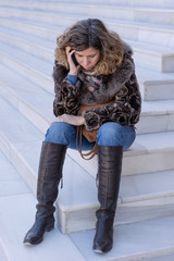 Fototapeta na wymiar Woman sitting on stairs talking on the phone