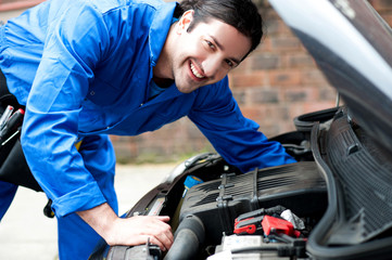 Young handsome mechanic looking at camera