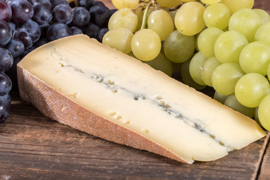 French morbier cheese with black and white grapes