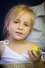 Beautiful little girl eating an apple