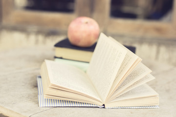 Open book and apple on a wooden table, vintage photo effect