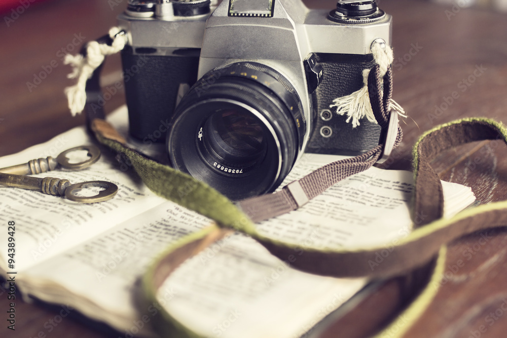 Poster Old book with old style camera and keys on a wooden table
