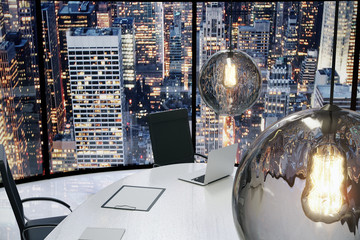 Modern office with vintage lightbulbs and city view at evening