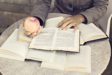Naklejka premium Girl reading a books outdoors with red apple