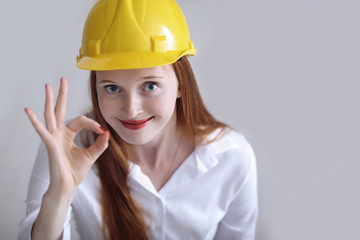 Long haired happy girl with yellow helmet showing the okey sign