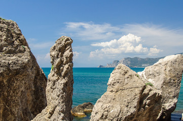 Broken rocks on the bank of the blue sea with blue sky and clouds